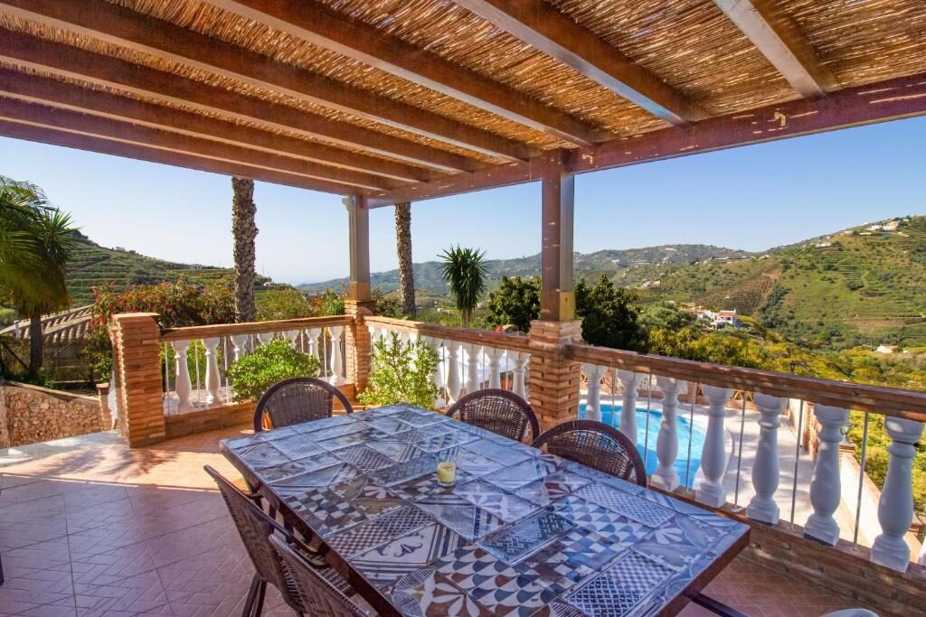 Überdachte Terrasse mit Blick auf Pool und Berge